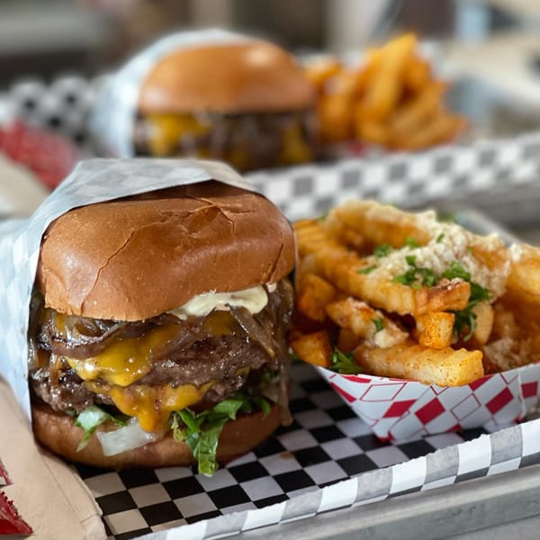A double cheeseburger with caramelized onions and a side of seasoned fries with parmesan and parsley.
