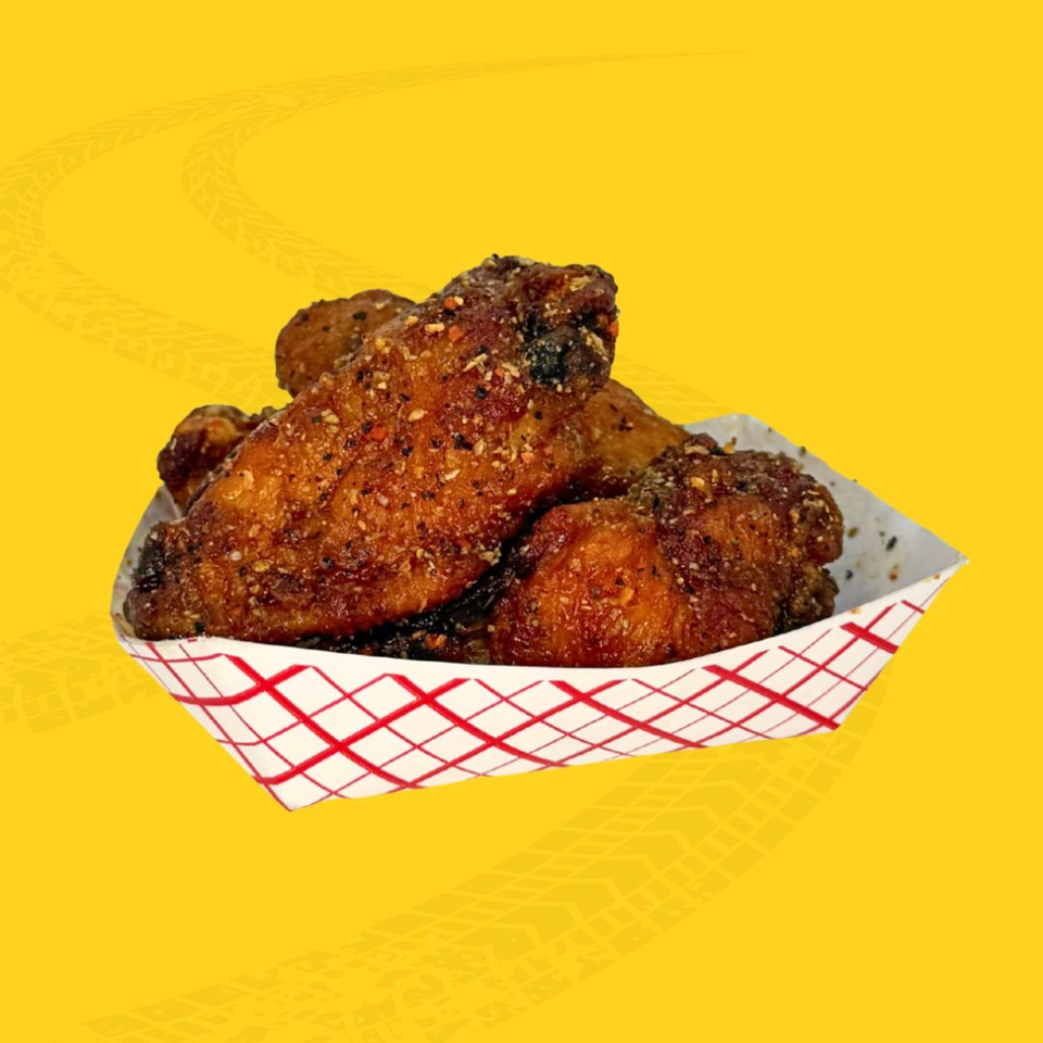 Basket of crispy seasoned fried chicken pieces in a red-and-white checkered liner against a bright yellow background.